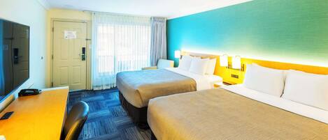 A hotel room with two beds, a desk, a chair, and a television.