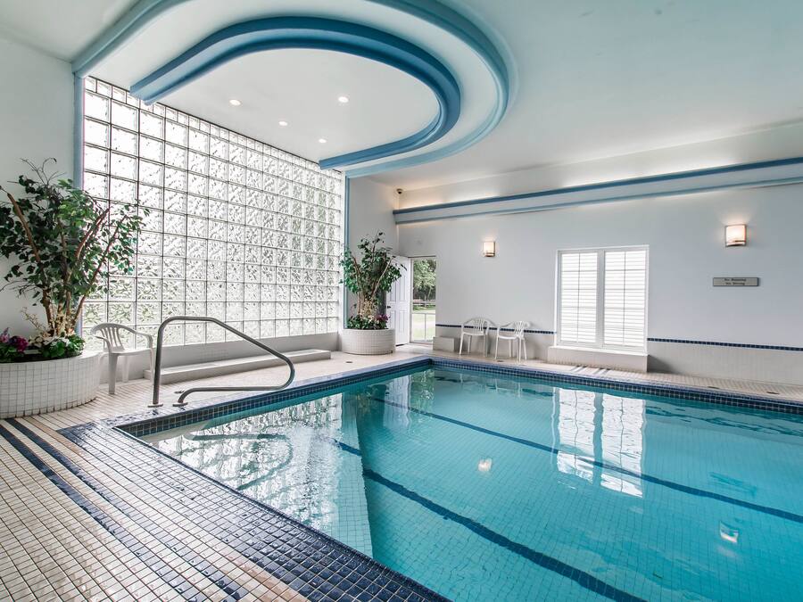 A swimming pool with a tiled floor and a glass partition wall.