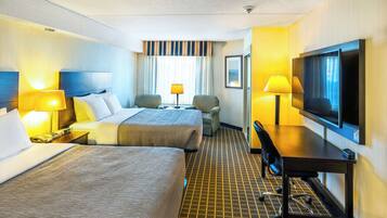 Une chambre d’hôtel avec deux lits, un bureau avec une télévision, une chaise et une lampe.