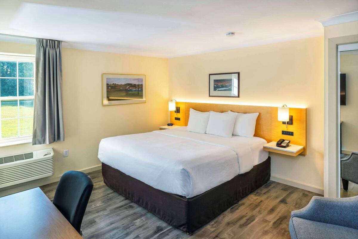 A hotel room with a large bed, bedside tables with lamps, a desk, and a chair.