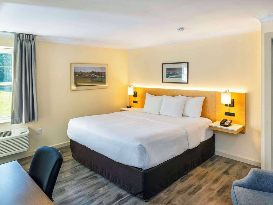 A hotel room with a large bed, bedside tables with lamps, a desk, and a chair.