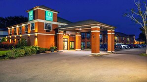 A hotel with a brick facade, a covered entrance, and a parking lot. - Quality Inn & Suites Garden of the Gulf (Summerside)