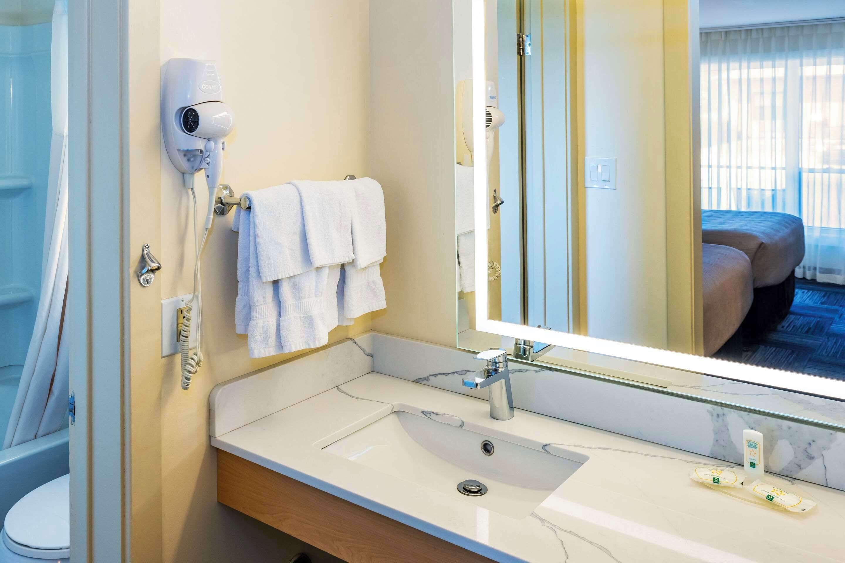 A hotel bathroom with a sink, mirror, towel rack, and a hairdryer.