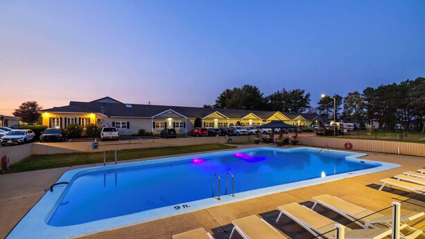 A swimming pool with lounge chairs and a building in the background. - Quality Inn & Suites Garden of the Gulf (Summerside)