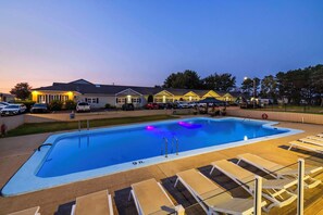 A swimming pool with lounge chairs and a building in the background. - Quality Inn & Suites Garden of the Gulf (Summerside)
