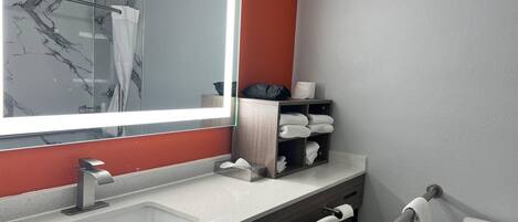 Ein modernes Badezimmer mit einem großen Spiegel, einem Waschbecken, einer Toilette und einem Handtuchhalter.