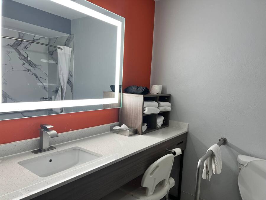 A modern bathroom with a large mirror, a sink, a toilet, and a towel rack.