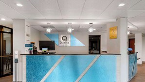 Un mostrador de recepción de hotel con un diseño de fuente de agua azul, un letrero que dice "Quality by Choice Hotels" y una pantalla digital.