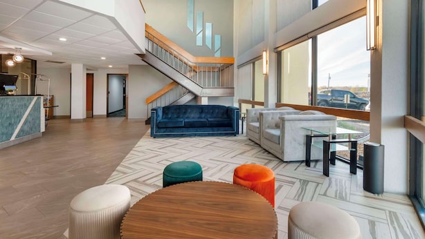 Un vestíbulo amplio con una escalera, un sofá azul y una mesa de madera.