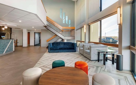 A spacious lobby with a staircase, a blue sofa, and a wooden table.