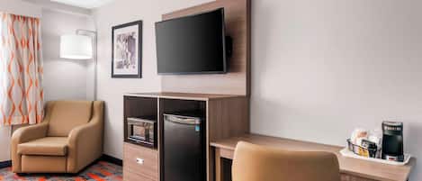 Habitación de hotel con sofá, escritorio con televisor de pantalla plana, minibar, microondas y cafetera.