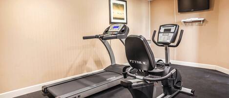 A gym with a treadmill and an elliptical machine.