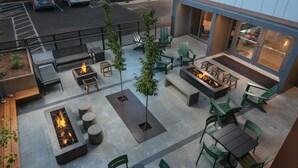 Un espace extérieur aménagé en terrasse, avec des sièges, des foyers et une vue sur la rue.