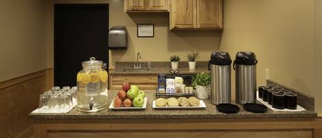 Una encimera de cocina con un frutero, cafeteras y un dispensador de agua.