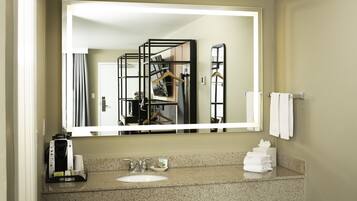 A bathroom with a large mirror, a sink, and a towel rack.