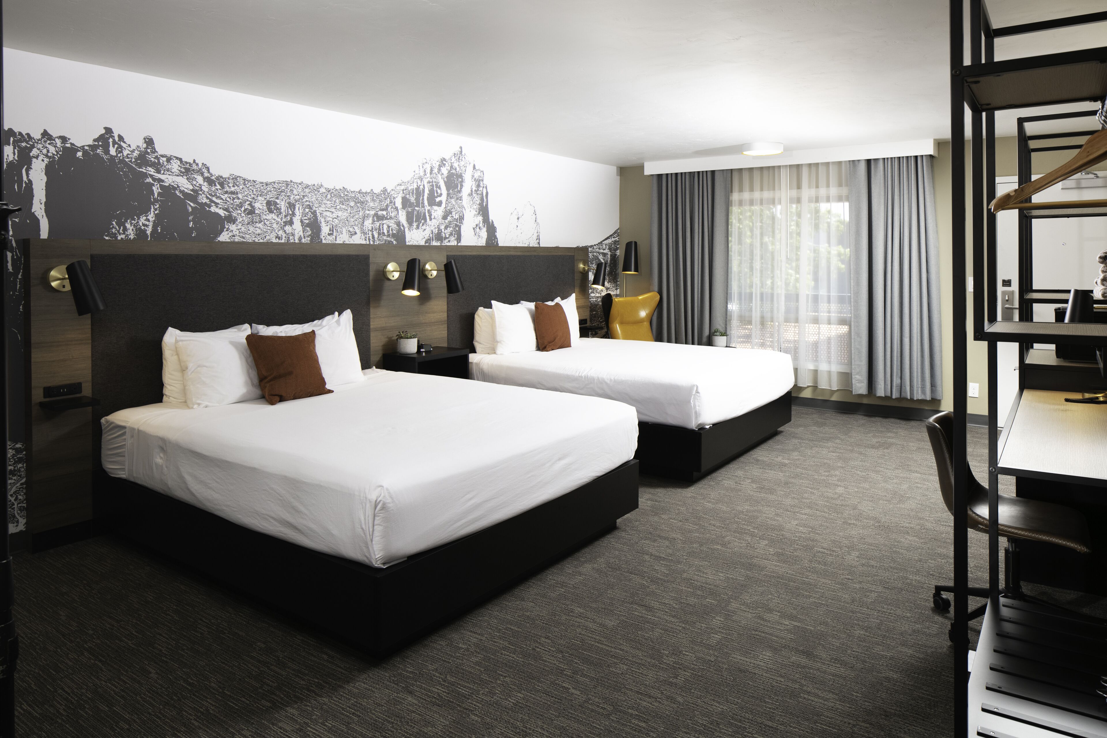 Quarto de hotel com duas camas, uma escrivaninha e uma cadeira.