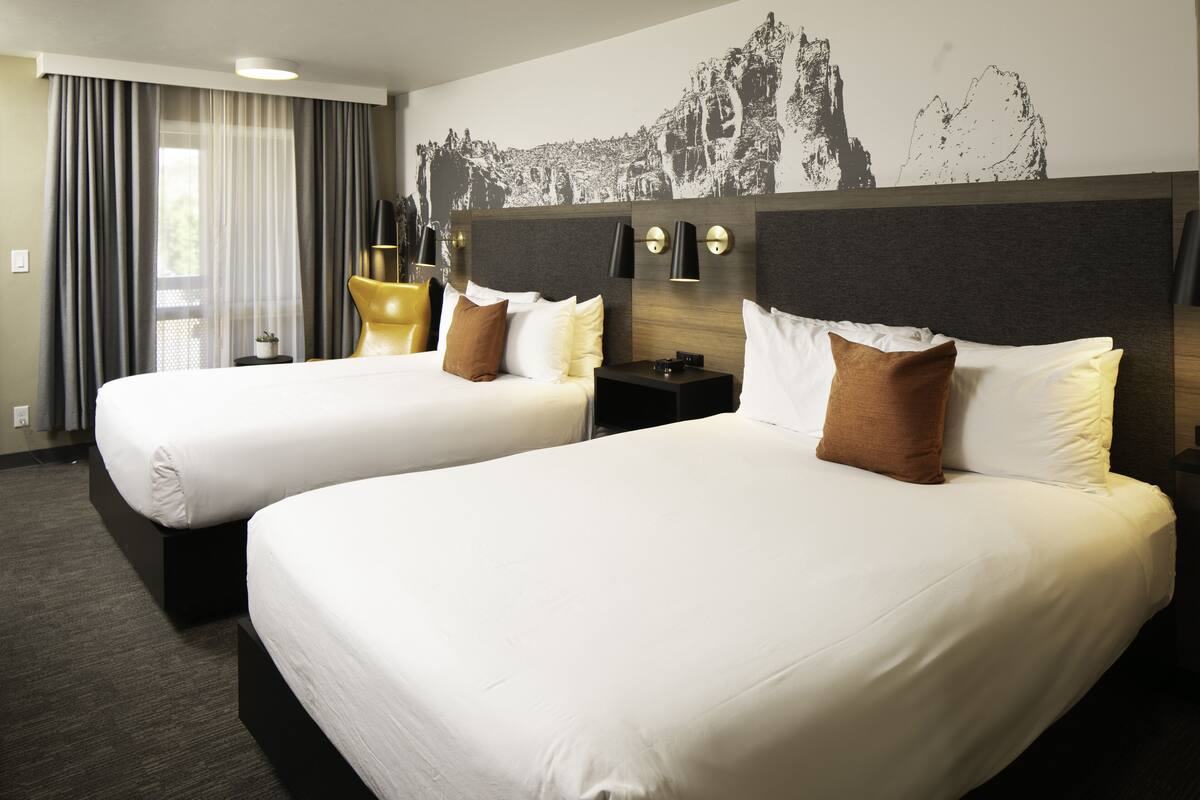 Quarto de hotel com duas camas, um mural grande na parede e design moderno.