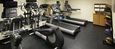 A gym with treadmills, elliptical machines, and exercise balls.
