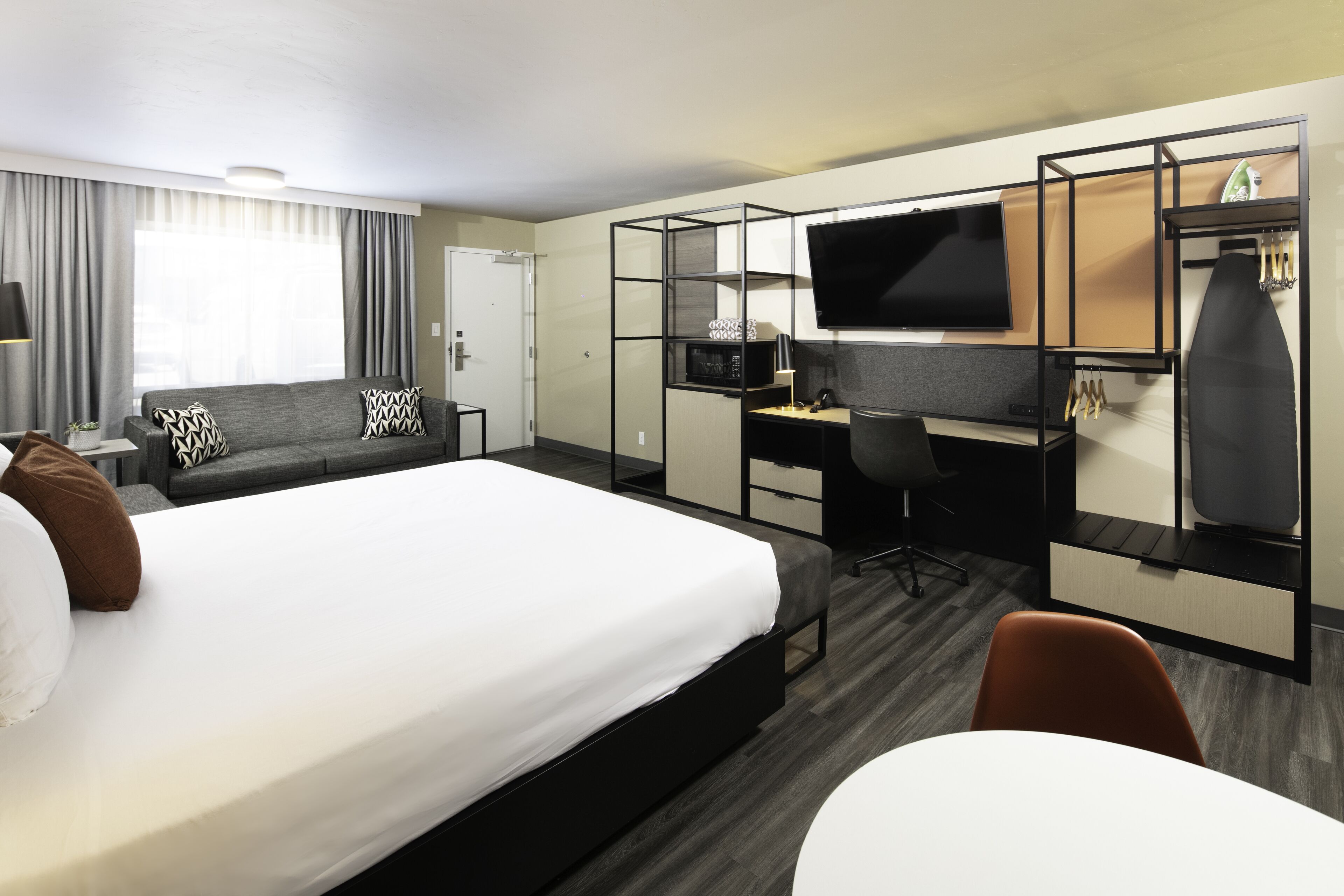 Een hotelkamer met een groot bed, een bureau met een computer, een televisie en een kledingkast.