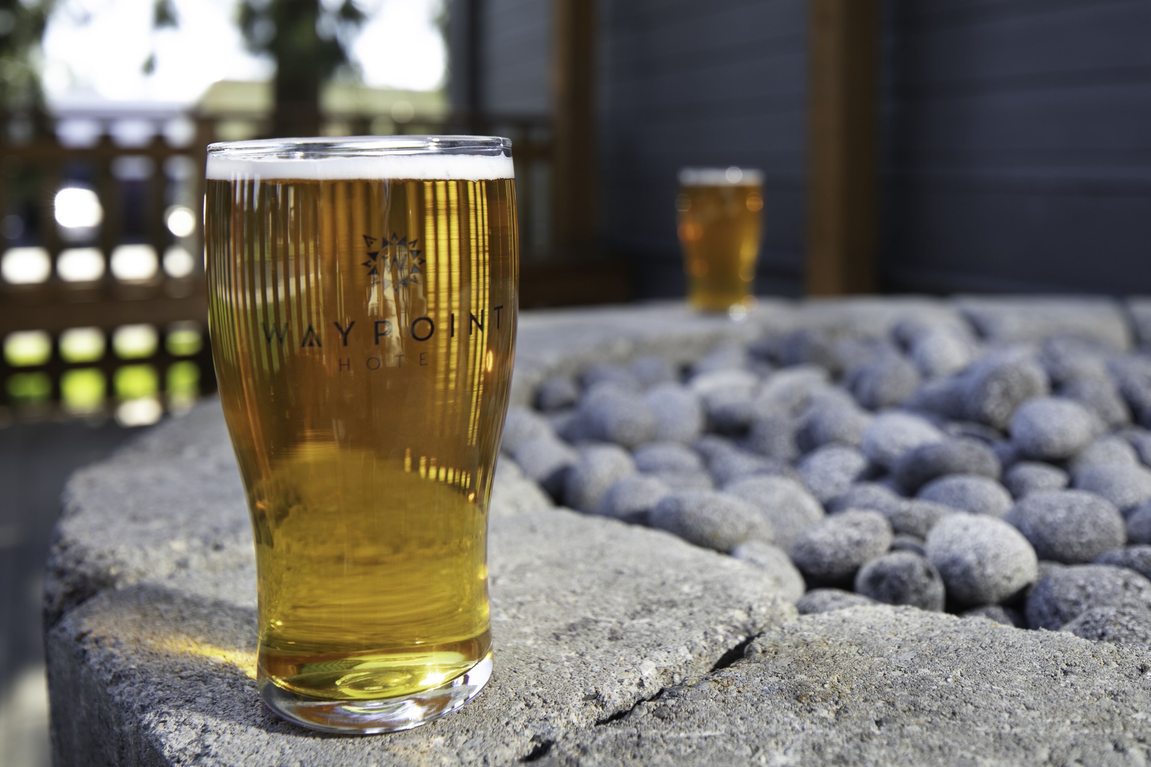A glass of beer on a stone surface with a blurred background.