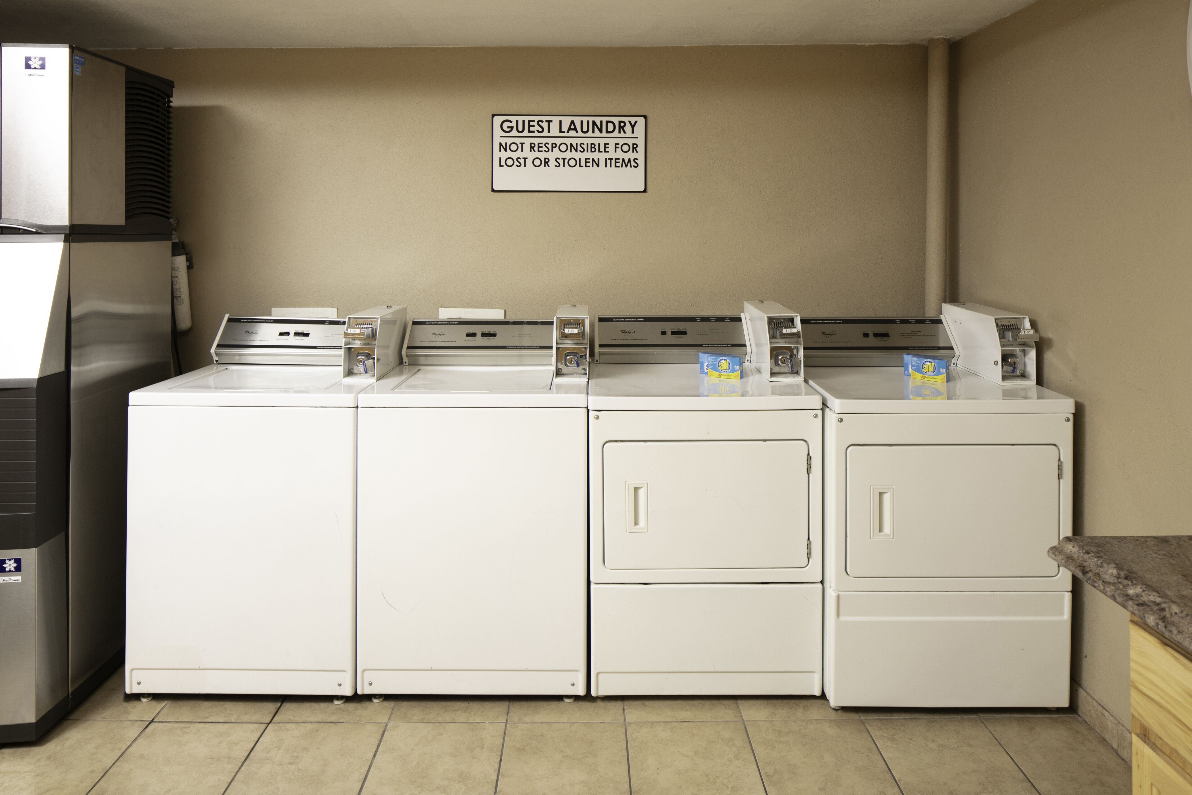 Een wasserette met vier wasmachines en drogers, een bordje dat aangeeft dat het voor gasten is, en een bericht over verloren of gestolen spullen.