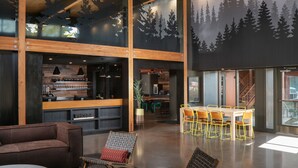 Un intérieur spacieux comprenant un bar, des espaces de détente et une fresque murale sur le thème de la forêt.