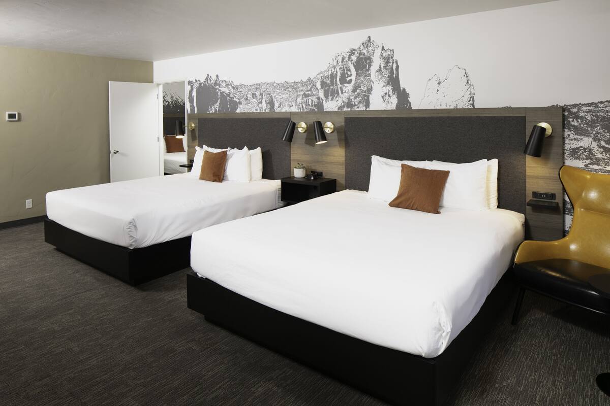 Quarto de hotel com duas camas, um mural grande na parede e design moderno.