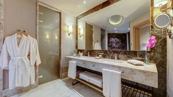 A modern bathroom with a marble vanity, a large mirror, and a glass shower enclosure.