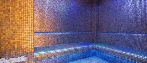 A spa area with mosaic tiled walls and benches.