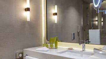 A modern bathroom with two sinks, a large mirror with a built-in light, and a toilet paper holder.