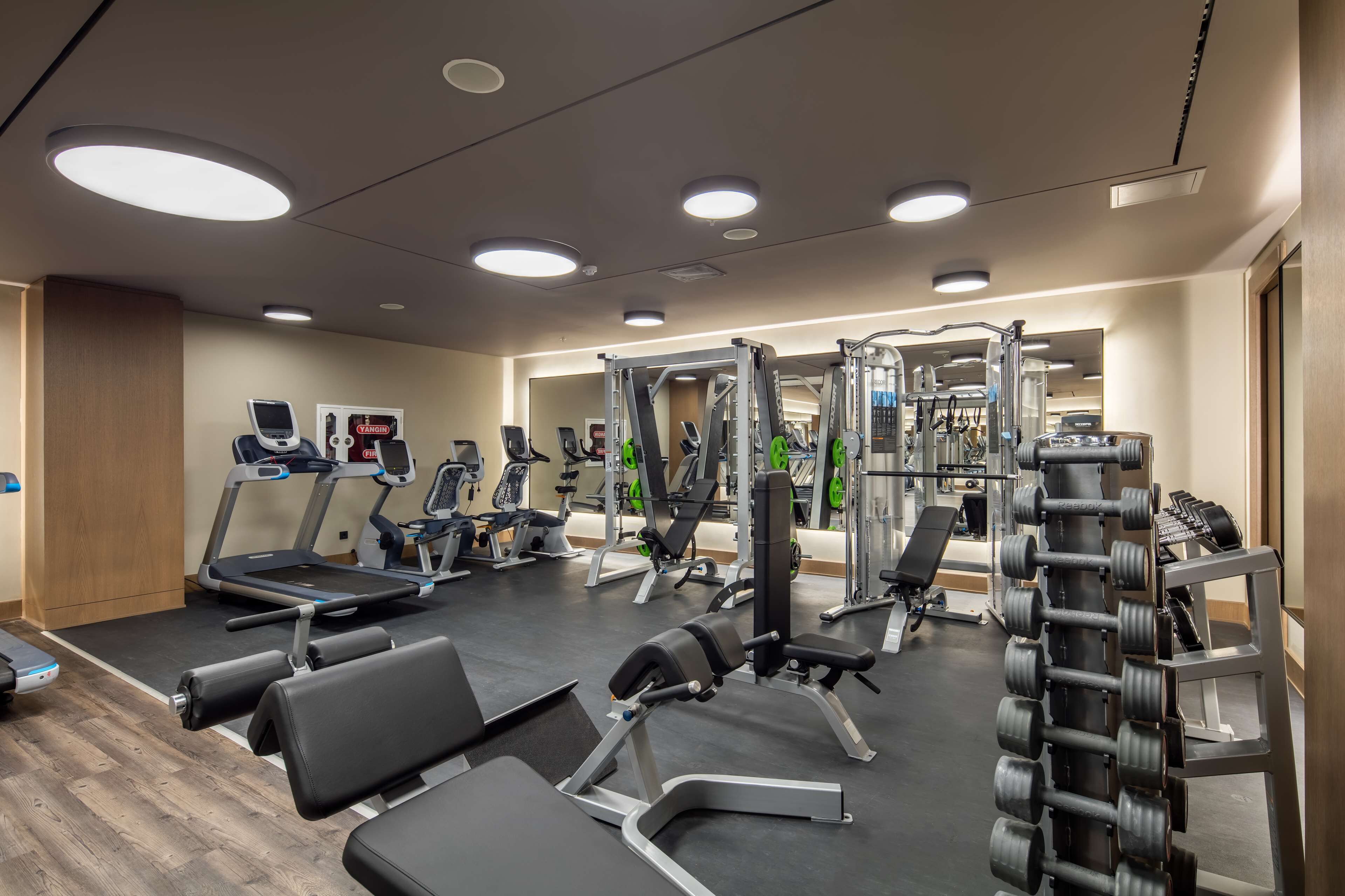 A gym with treadmills, weight machines, and dumbbells.