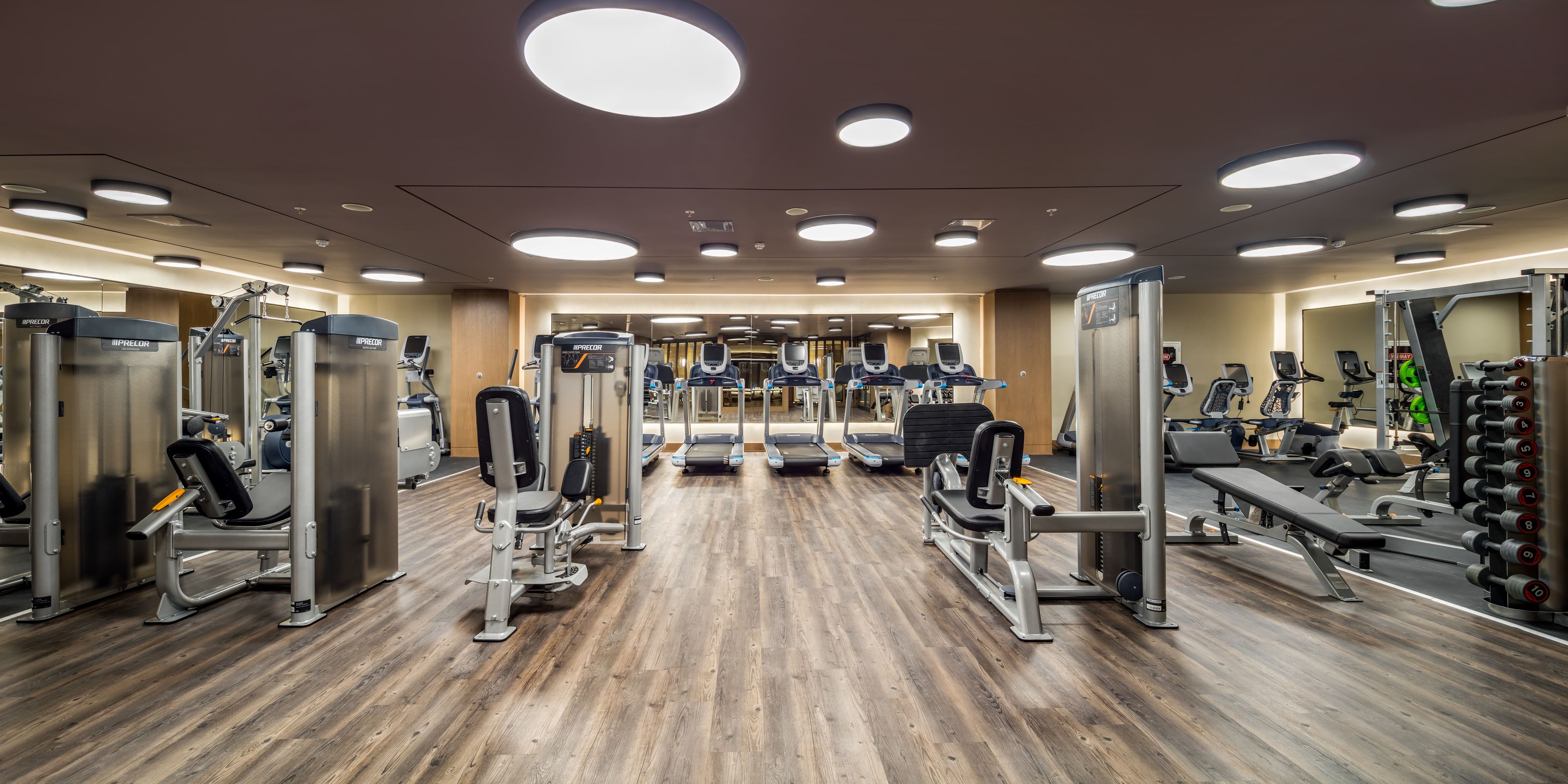 Ein Fitnessstudio mit verschiedenen Trainingsgeräten, Laufbändern und Gewichten.