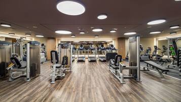 Ein Fitnessstudio mit verschiedenen Trainingsgeräten, Laufbändern und Gewichten.