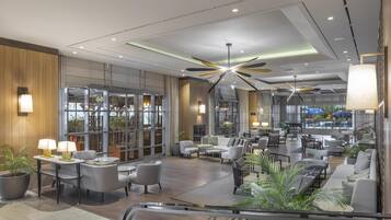 A spacious lobby with modern furniture, a ceiling fan, and large windows offering views of the outdoors.