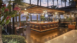 A bar area with a wooden counter, bar stools, and a view of the ocean. - Mersin HiltonSA (Mersin)