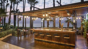 A wooden bar with bar stools, a pool table, and a view of the ocean. - Mersin HiltonSA (Mersin)