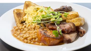 A plate of food including toast, scrambled eggs, beans, bacon, and mushrooms.