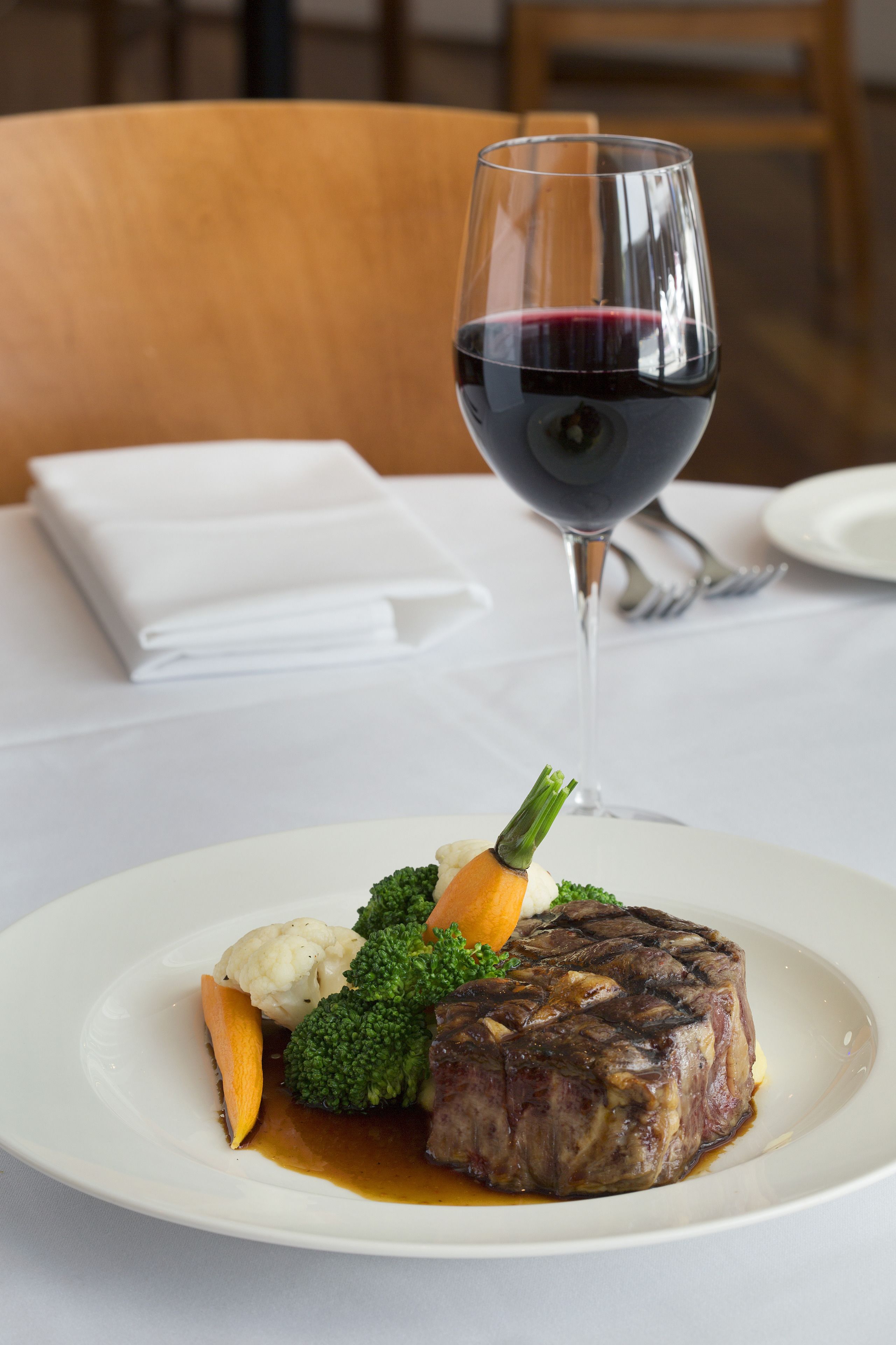 A plate of food with a glass of red wine on a table.