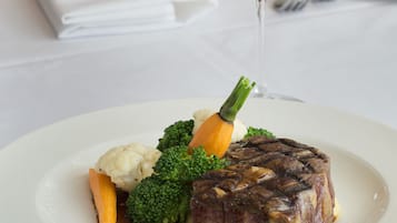 A plate of food with a glass of red wine on a table.