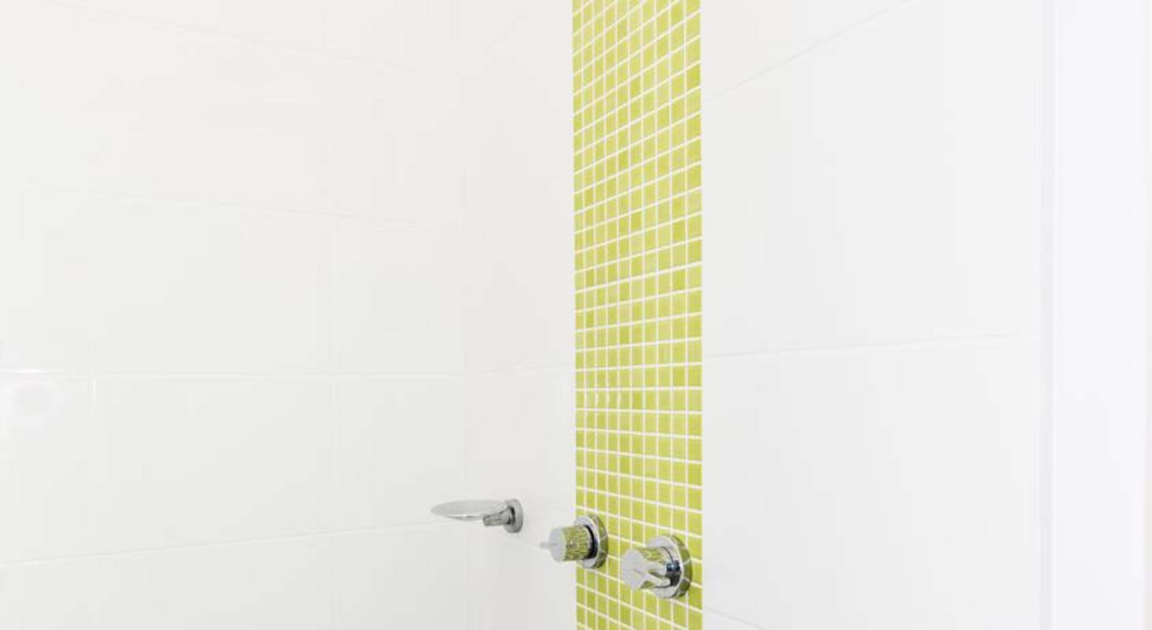 Un bagno con piastrelle bianche e una parete decorata con piastrelle verdi.