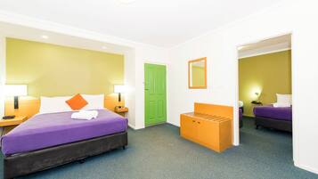 A hotel room with a large bed, a bench, a green door, and a mirror on the wall.