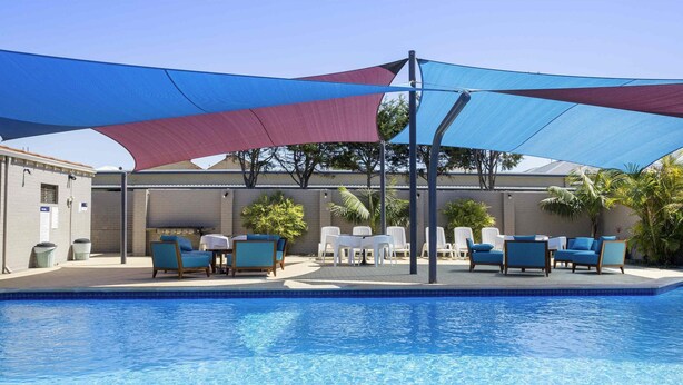 A swimming pool with lounge chairs and a shaded area. - ibis Styles Geraldton (Tarcoola Beach)