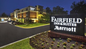 Une enseigne indiquant l’emplacement du Fairfield Inn & Suites Marriott, avec un parking et des bâtiments en arrière-plan.
