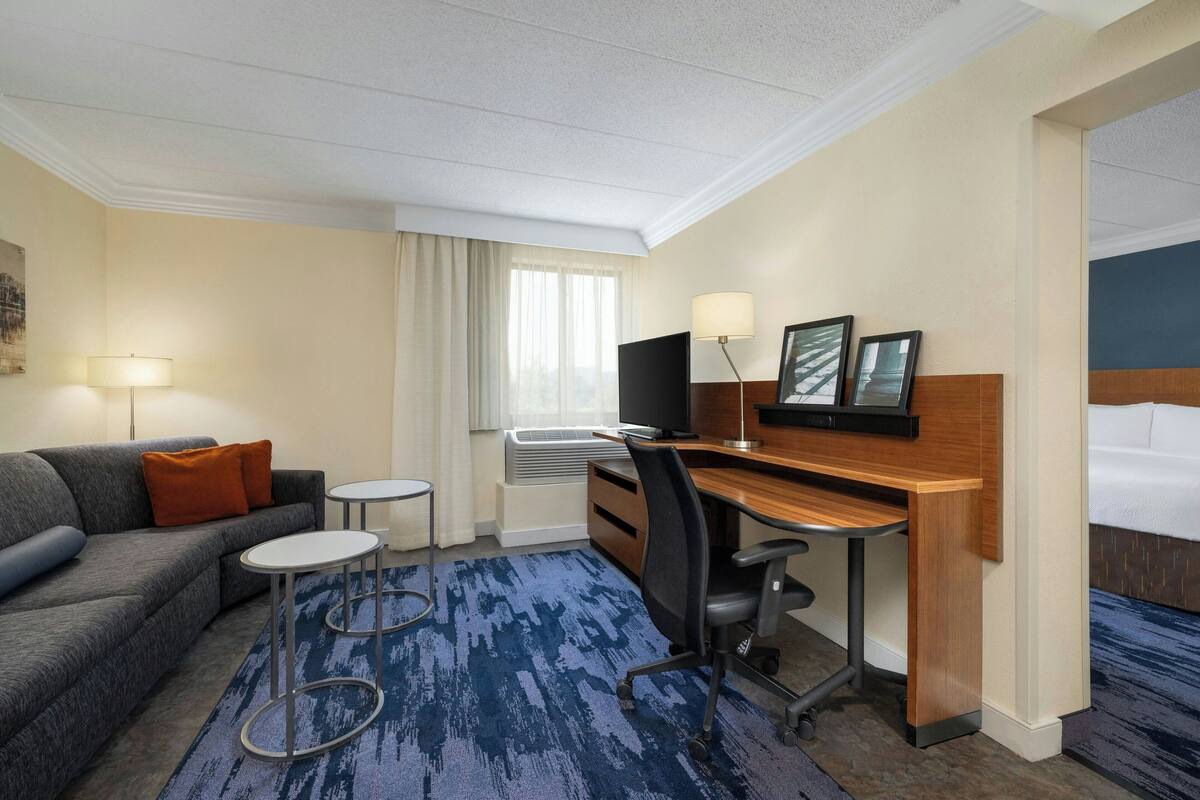 Habitación de hotel con sofá, escritorio, silla, mesita y cama.