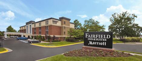 A Fairfield Inn & Suites Marriott hotel with a brick facade, a parking lot, and a sign in the foreground.