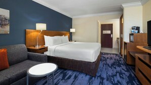 Une chambre d’hôtel avec un lit, un canapé, une petite table et un bureau avec une lampe.