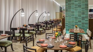 A restaurant with multiple dining tables, chairs, and a green tiled wall. - DoubleTree by Hilton Laredo (Laredo)