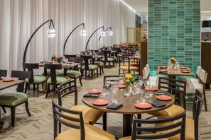 Un restaurant doté de plusieurs tables, de chaises et d’un mur recouvert de carreaux verts.
