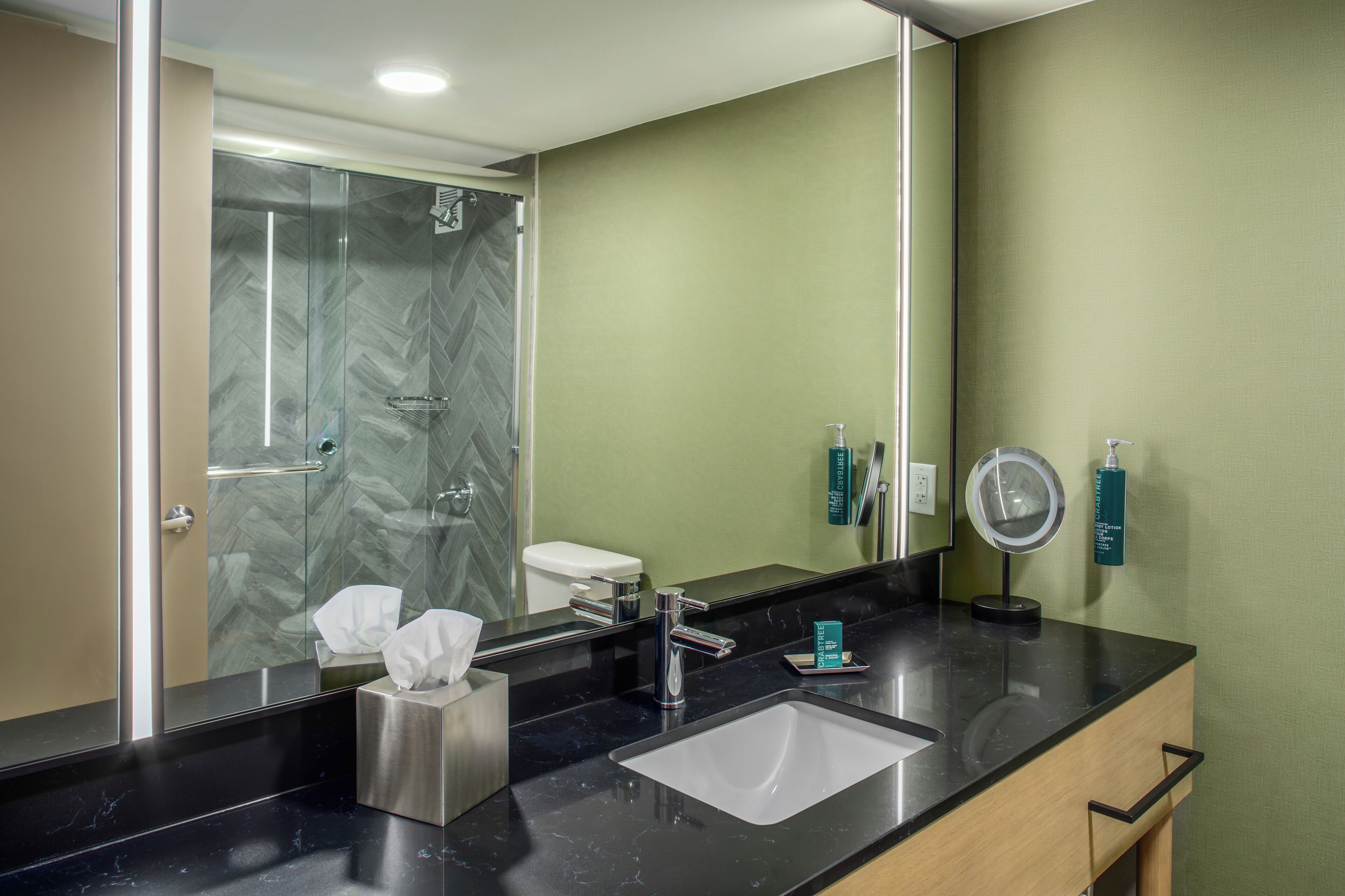 A modern bathroom with a glass shower, a sink, and a mirror.