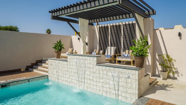 A pool area with a pergola, lounge chairs, and potted plants. - DoubleTree by Hilton Laredo (Laredo)